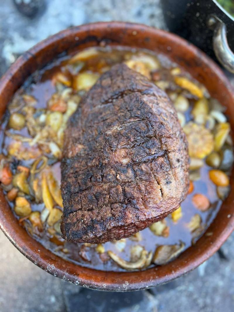 Pieza de carne asada servida en cazuela de barro con verduras