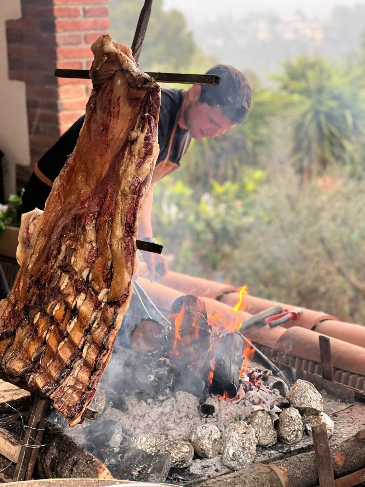 Costillar argentino asándose a la cruz junto al fuego, técnica tradicional de asado a la parrilla