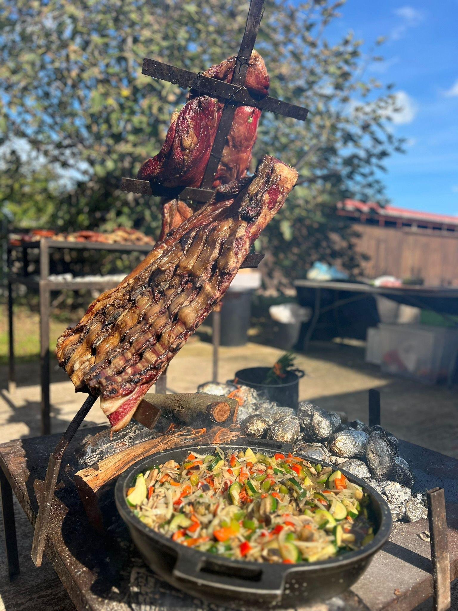 Cruz de asado junto al fuego con cazuela de verduras salteadas